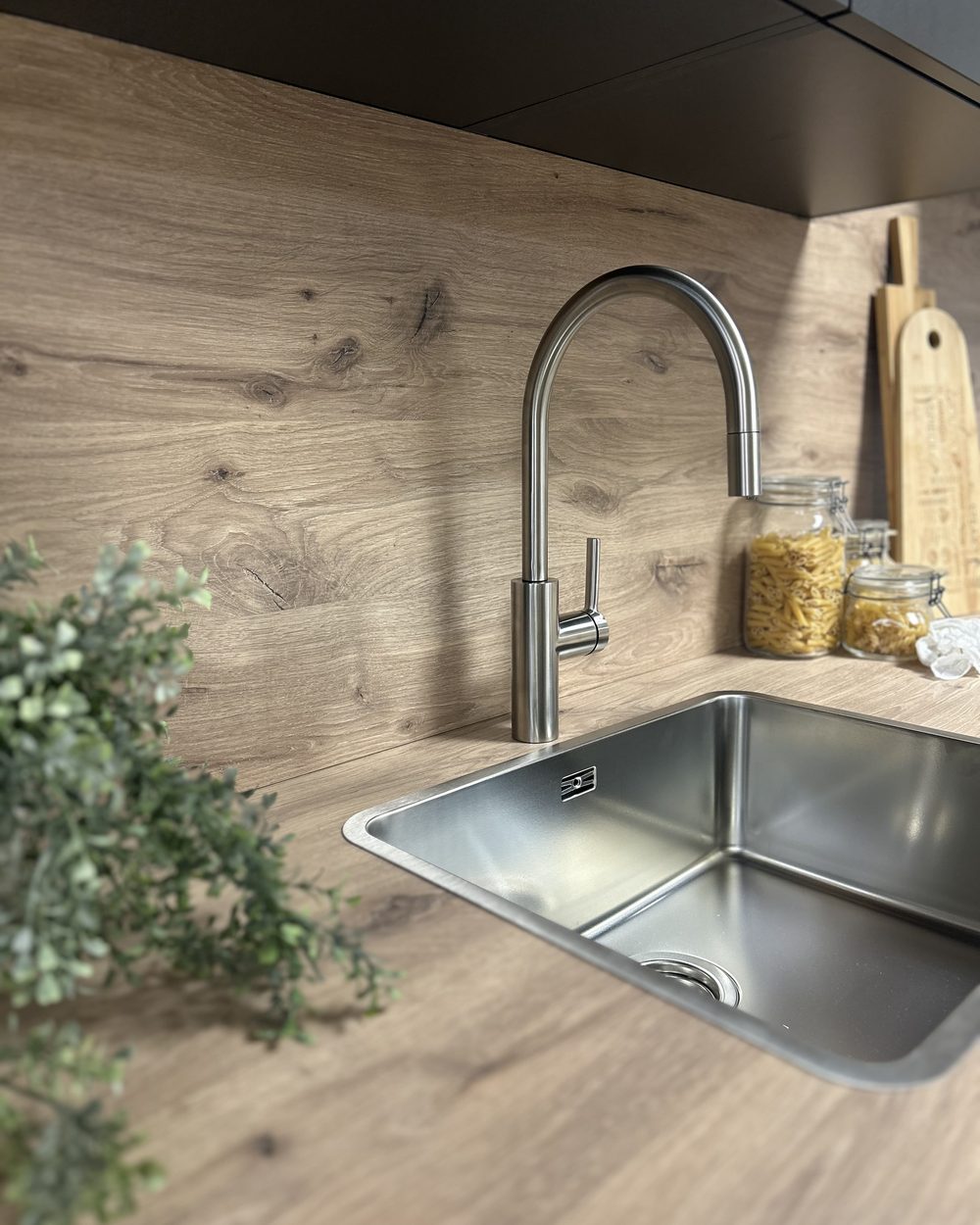 Laverno kraan in RVS boven een RVS spoelbak, met een eiken achterwand en planten